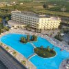 Un grande hotel con piscina a forma irregolare e sdraio tutto intorno.